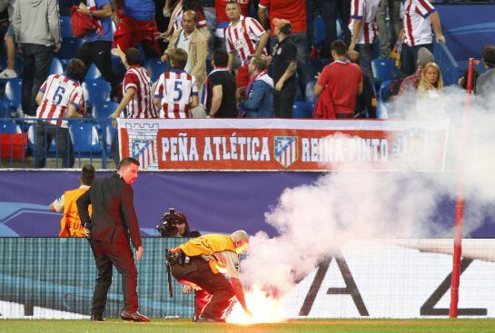 Un trabajador de la seguridad del Calderón retira una bengala del terreno de juego durante el partido entre el Atlético y el Benfica.