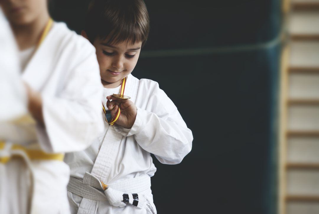 Niño observando la medalla que acaba de ganar.