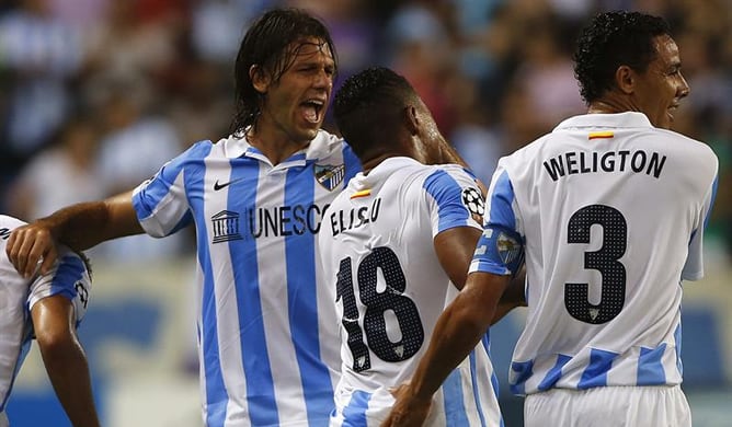 El portugués Eliseu Pereira, defensa del Málaga, celebra el segundo gol de su equipo frente al Panathinaikos con sus compañeros Martín Demichelis y Weligton Robson, durante el partido de ida de la última ronda previa de la Liga de Campeones en el estadio 