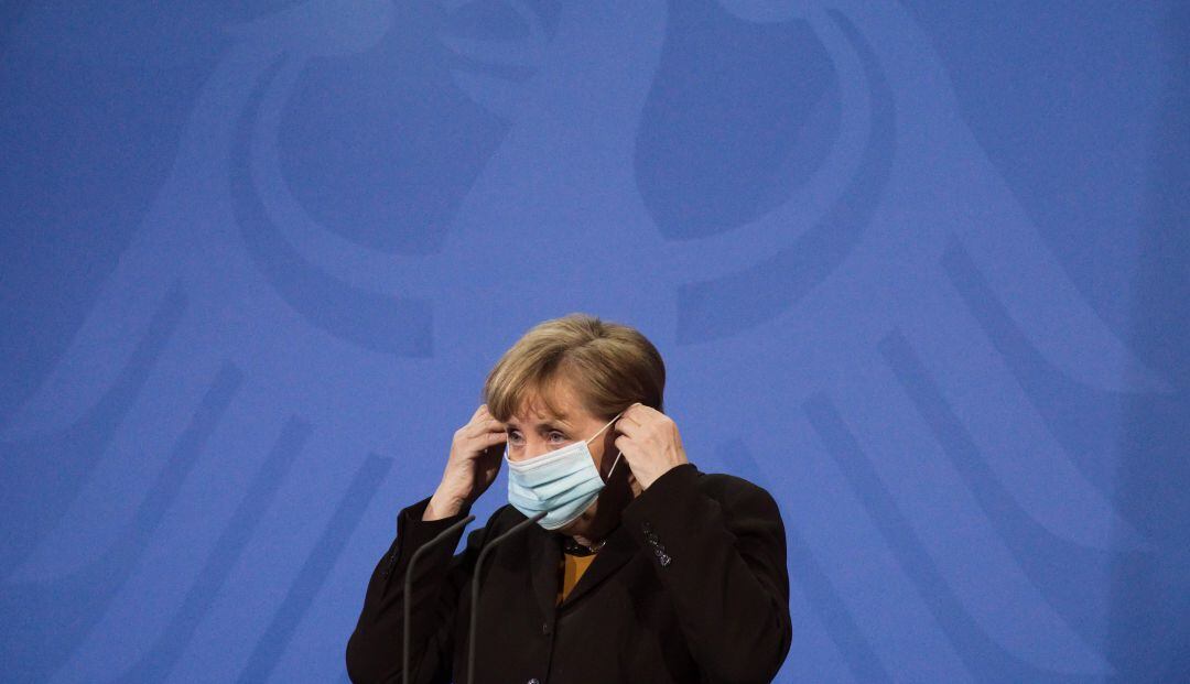 Ángela Merkel se pone una máscarilla en una rueda de prensa.