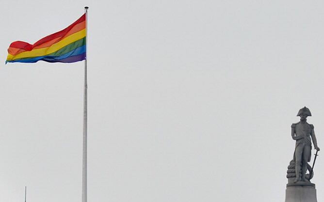 La bandera del orgullo gay onde delante de la estatua de Horatio Nelson en la cima de la columna de Nelson, en el centro de Londres