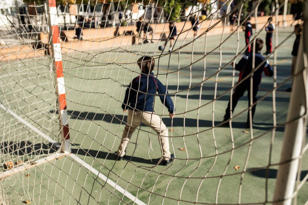 Varios niños juegan al fútbol en el patio de un colegio