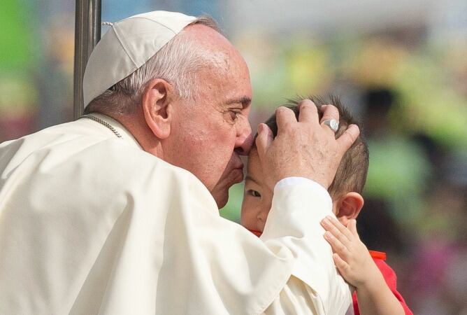 El papa Francisco besa a un niño durante su visita a Corea del Sur.