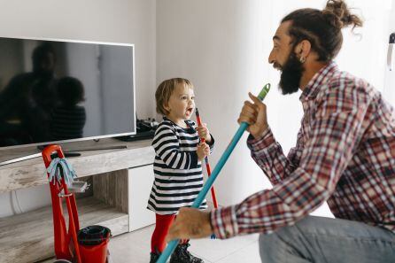 Padre e hija cantan mientras hacen las tareas de la casa