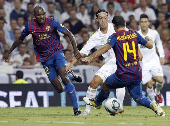 El defensa argentino del FC Barcelona, Javier Mascherano (d), intenta robarle la pelota al centrocampista alemán del Real Madrid, Mesut Özil (c), en presencia del defensa francés del Barça, Eric Abidal (i), durante el partido correspondiente a la ida de l