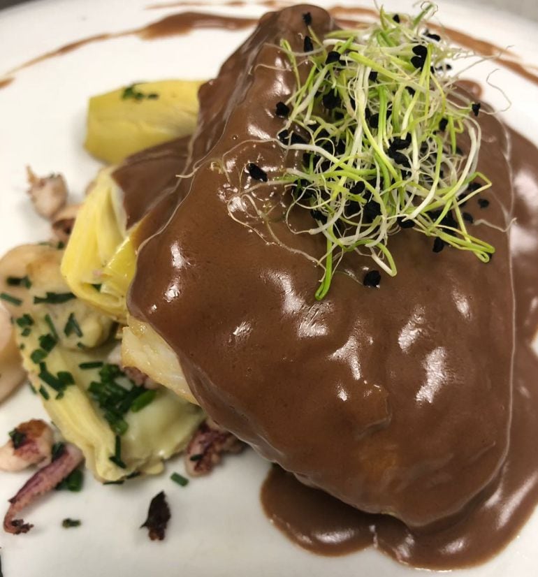 Bacalao confitado sobre alcachofas, chipirones y jugo de cacao de la Trapa