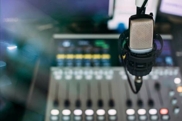 Close up of microphone on radio broadcast studio and sound mixing console on the background