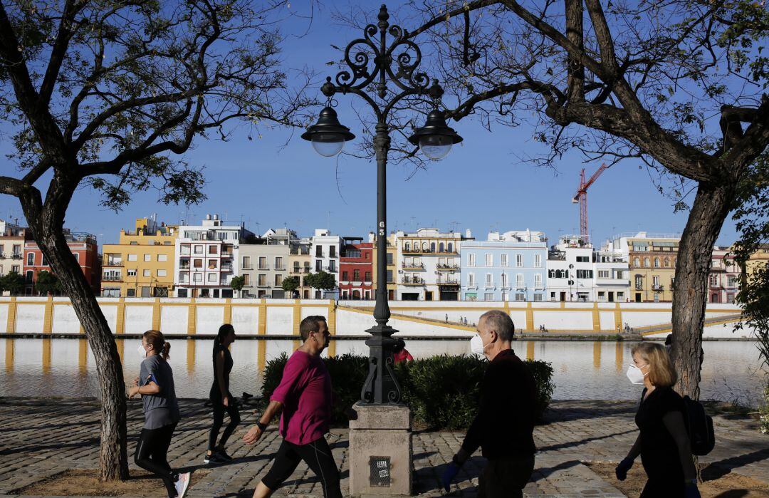 Varias mujeres y hombres hacen ejercicio a orillas del Guadalquivir en Sevilla, manteniendo la distancia de seguridad entre ellos.