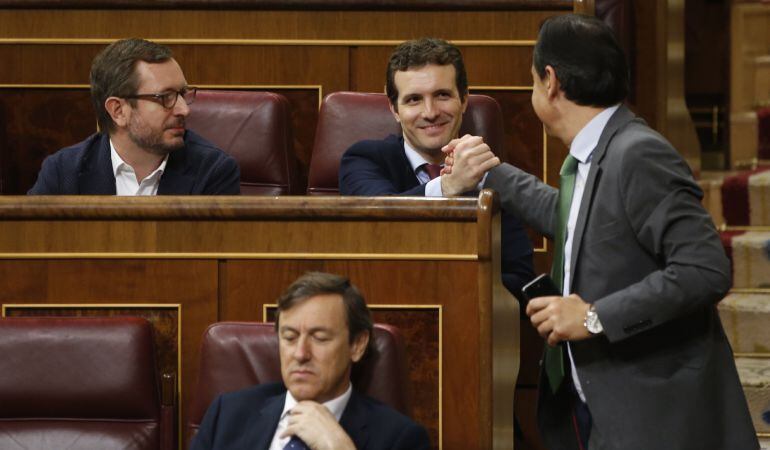 El diputado popular Fernando Martínez-Maíllo (d) saluda a su compañero de partido, Pablo Casado (2d), durante la sesión de control al Gobierno celebrada hoy en el Congreso.