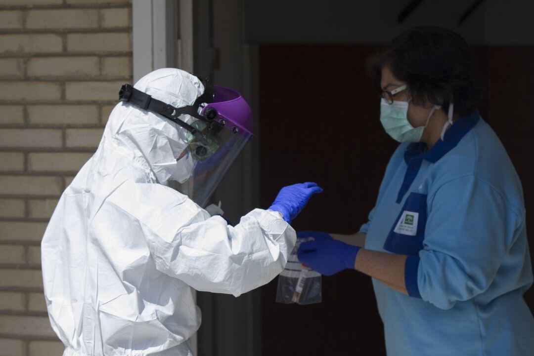 Un sanitario entrega las pruebas a otro, tras realizar una recogida de muestra desde el coche para detectar casos de coronavirus.