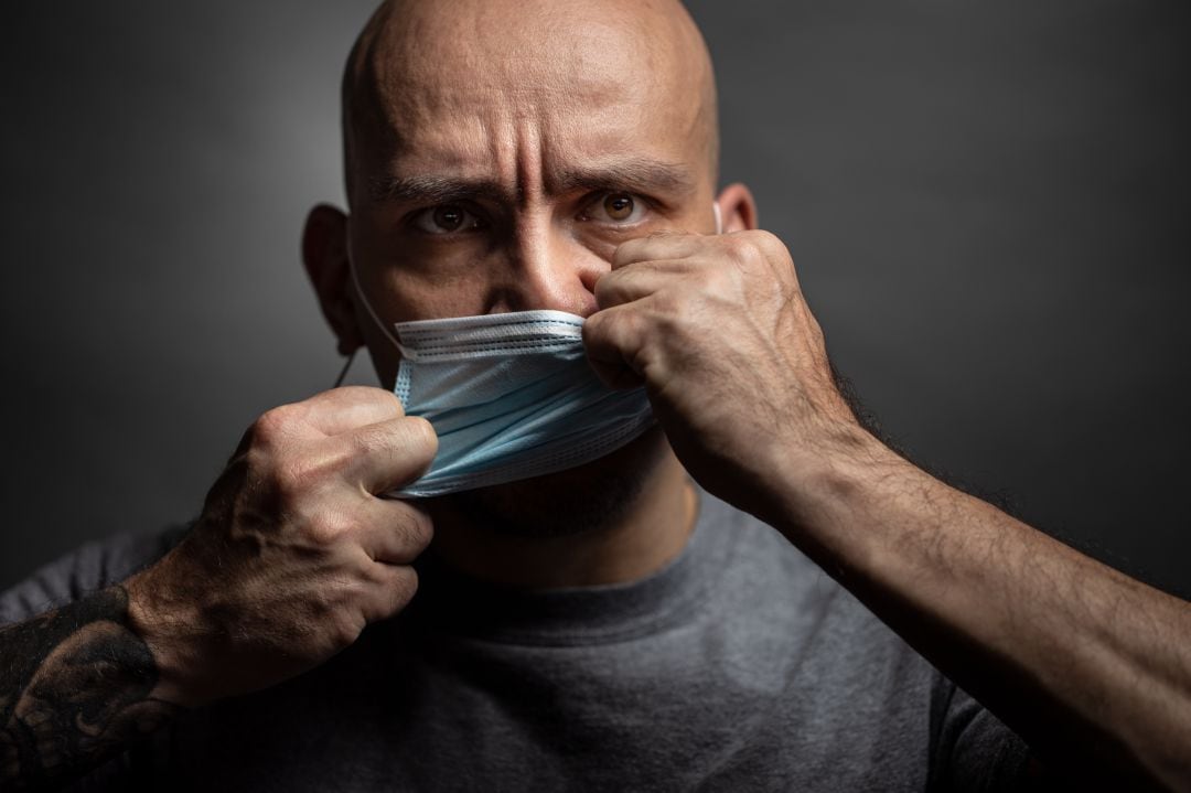 Un hombre muestra miedo al quitarse la mascarilla