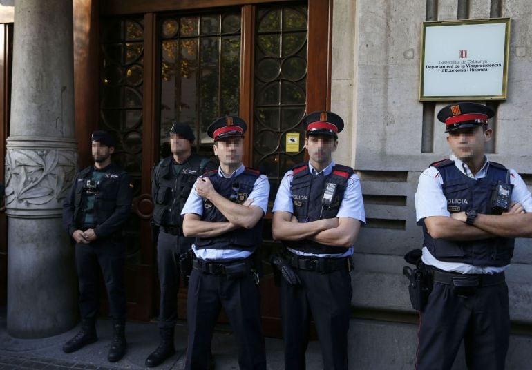 Agentes de la Guardia Civil y de los Mossos d&#039;Esquadra en la puerta de la consellería de Economía de la Generalitat, cuyo titular es Oriol Junqueras, donde agentes del instituto armado se han personado esta mañana en busca de documentación relacionada con el referéndum del 1-O, anulado por el Tribunal Constitucional. 