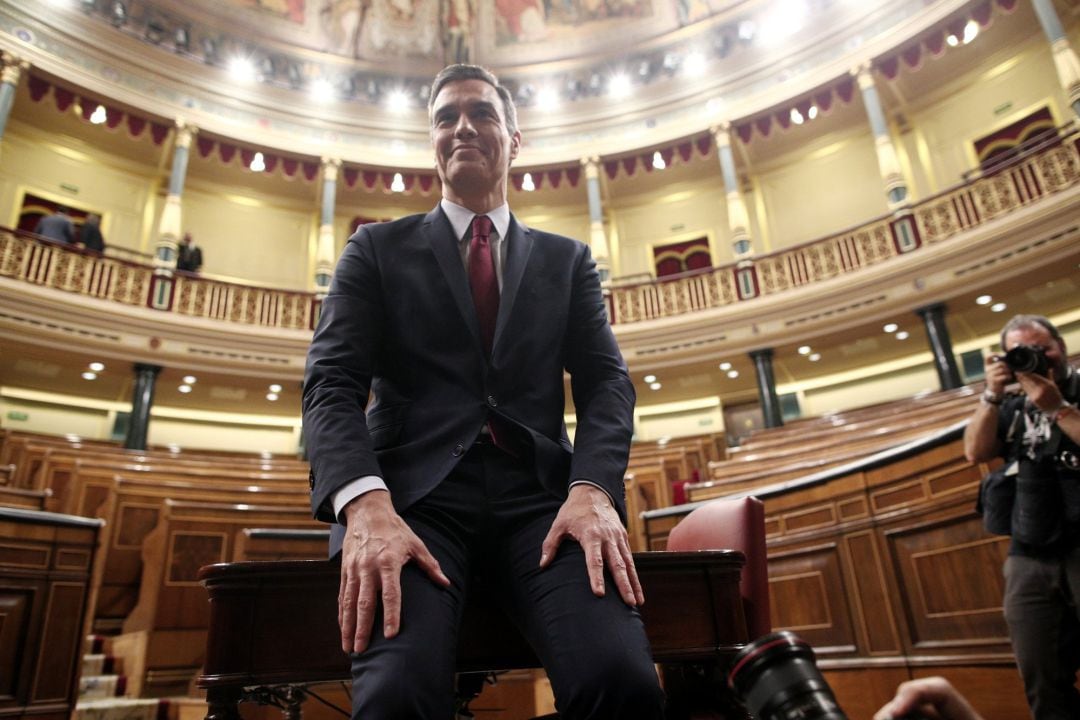 El presidente del Gobierno, Pedro Sánchez, posa sonriente en el hemiciclo del Congreso de los Diputados, tras obtener una votación favorable a su investidura 