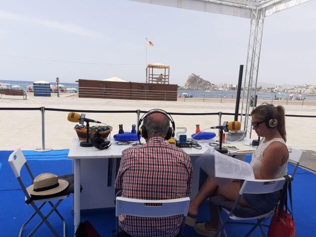 Juan Hernández, durante su entrevista en la Radio al Sol. Al fondo, la aguileña Playa de las Delicias