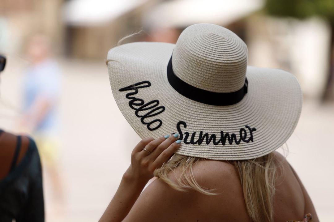 Una mujer se protege del calor con un sombrero.