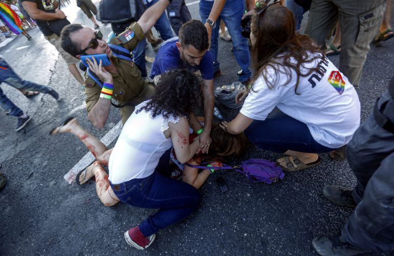 Varias personas tratan de ayudar a una de las seis personas apuñaladas mientras participaban en la Marcha del Orgullo Gay en Jerusalén.