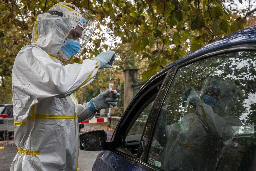 Un trabajador sanitario toma muestras de una prueba PCR practicada en unas carpas a las que se accede en coche, en una imagen de archivo