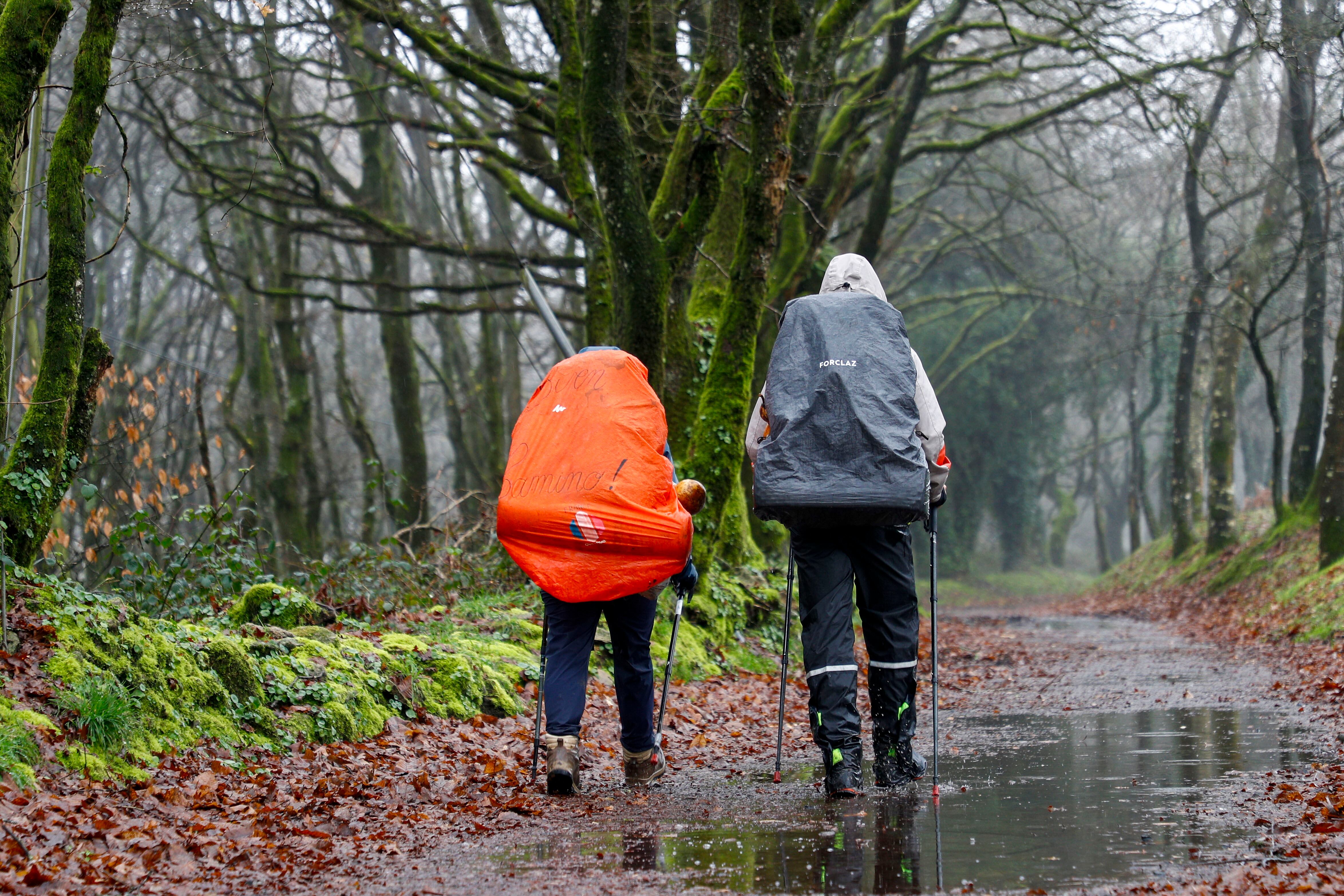 PALAS  DE REI (LUGO), 04/01/2024.- Dos peregrinos transitan por el Alto del Rosario, a su paso por Palas de Rei, este jueves, una jornada marcada por la inestabilidad y los chubascos en Galicia. EFE/ Eliseo Trigo
