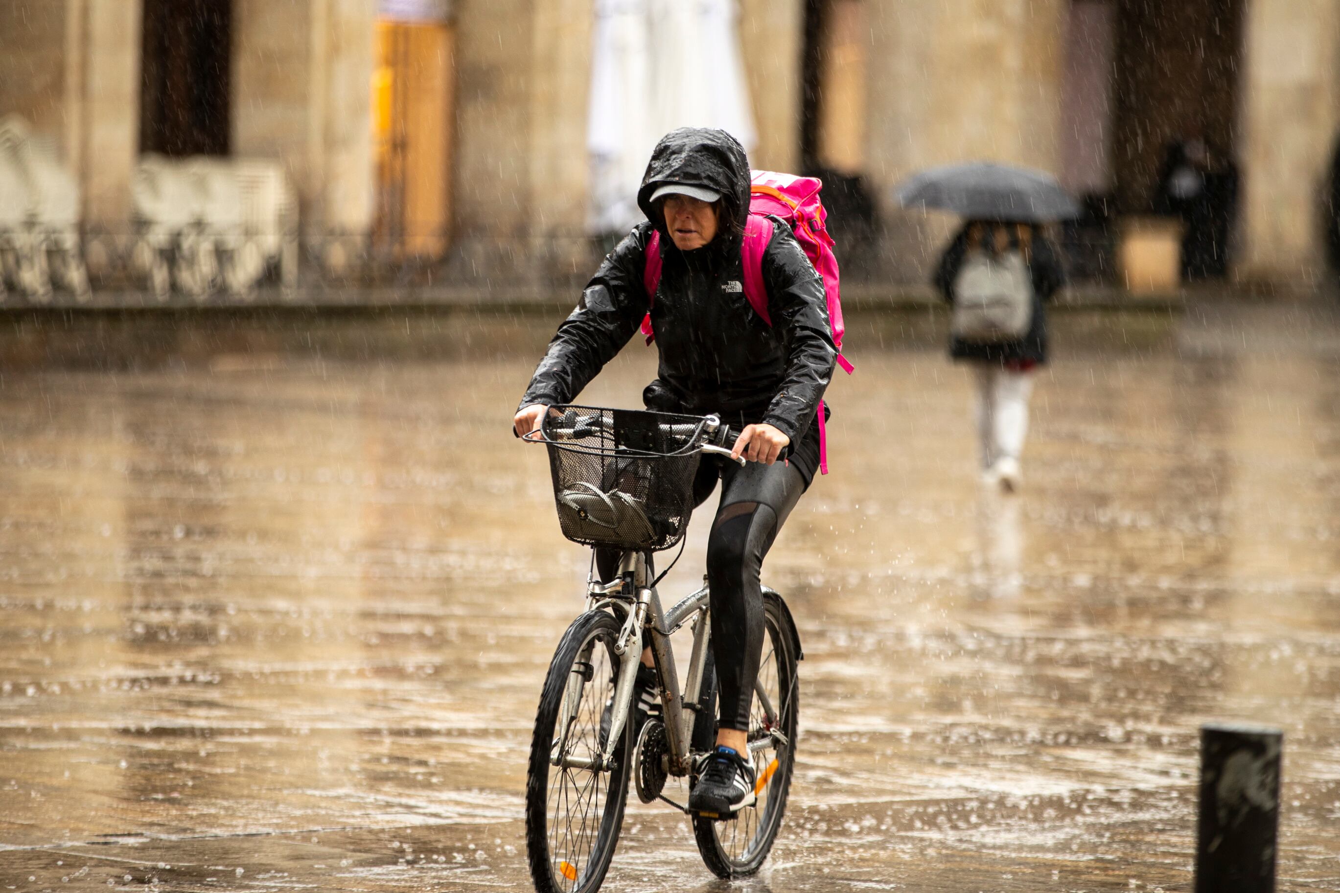 Una mujer pasa en bicicleta por la plaza Nueva de Vitoria bajo un fuerte chubasco EFE/David Aguilar