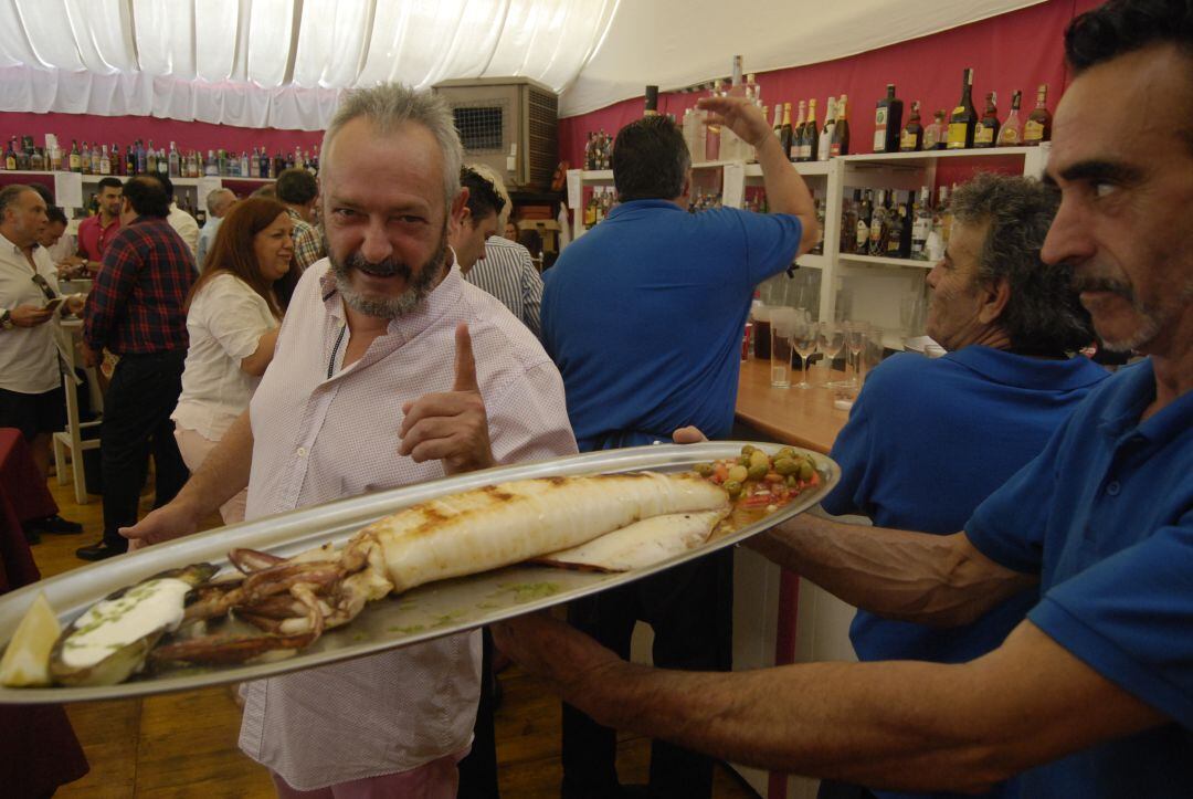 El empresario Antonio Tuset luce un espléndido calamar antes de servirlo en una de las mesas de la caseta &quot;Todos los jueves&quot;.