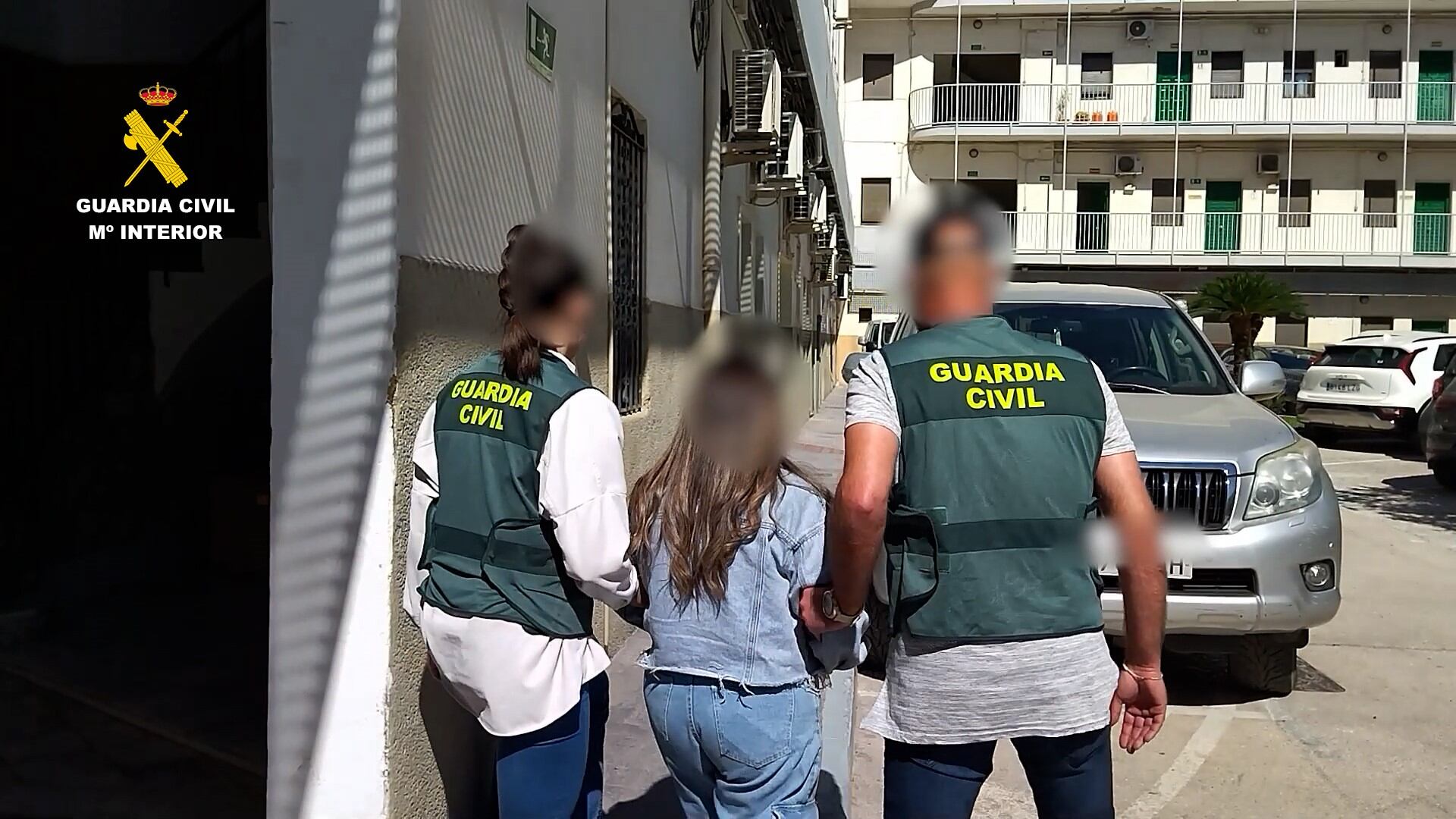 Dos agentes de la Guardia Civil con una de las mujeres detenidas por sextorsión