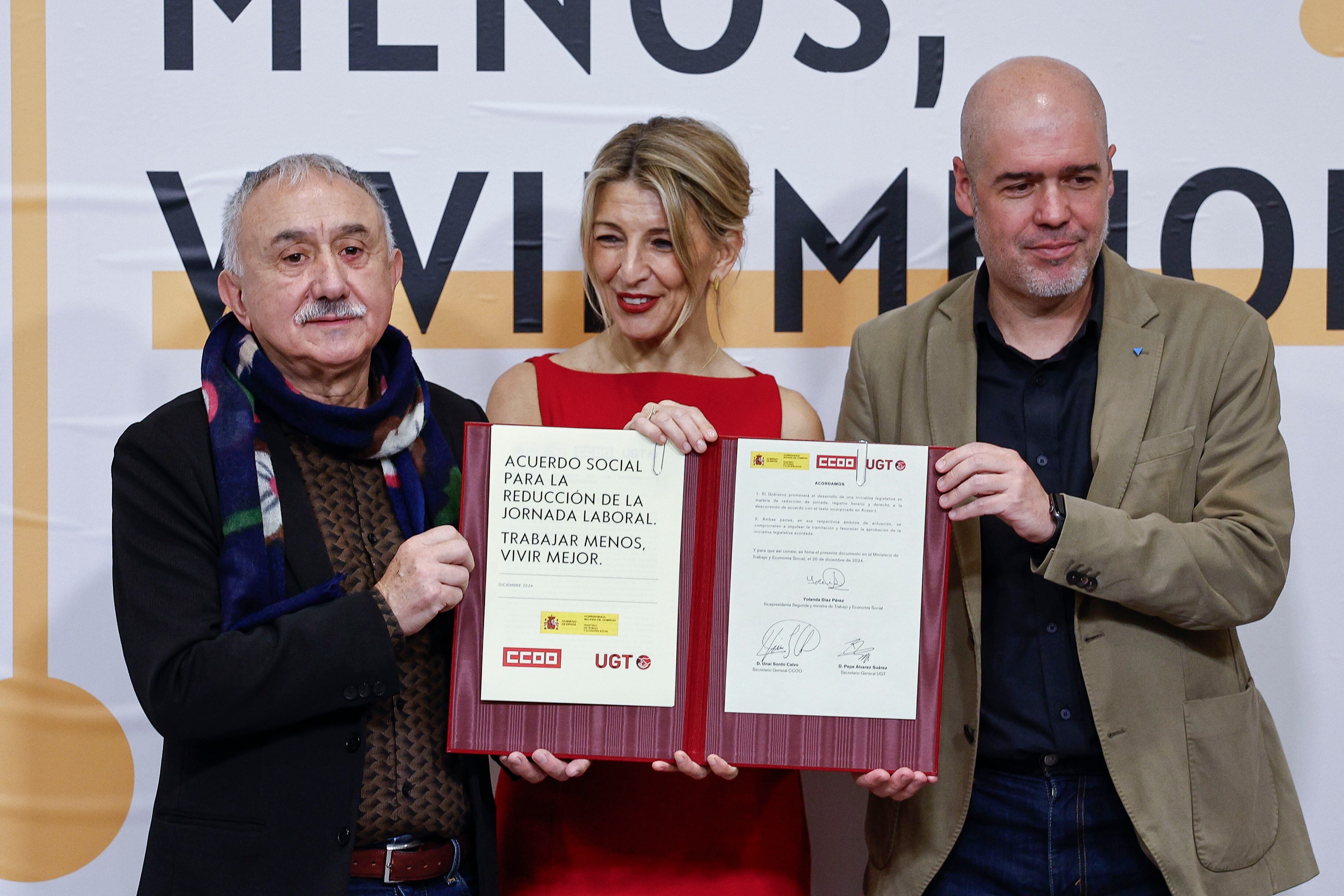 MADRID, 20/12/2024.- La vicepresidenta segunda del Gobierno y ministra de Trabajo, Yolanda Díaz (C), firma este viernes con los secretarios generales de CCOO y UGT, Unai Sordo (d) y Pepe Álvarez (i), respectivamente, el acuerdo alcanzado entre el Ejecutivo y los sindicatos para reducir la jornada laboral a 37 horas y media en 2025 sin reducción salarial. EFE/ Rodrigo Jimenez