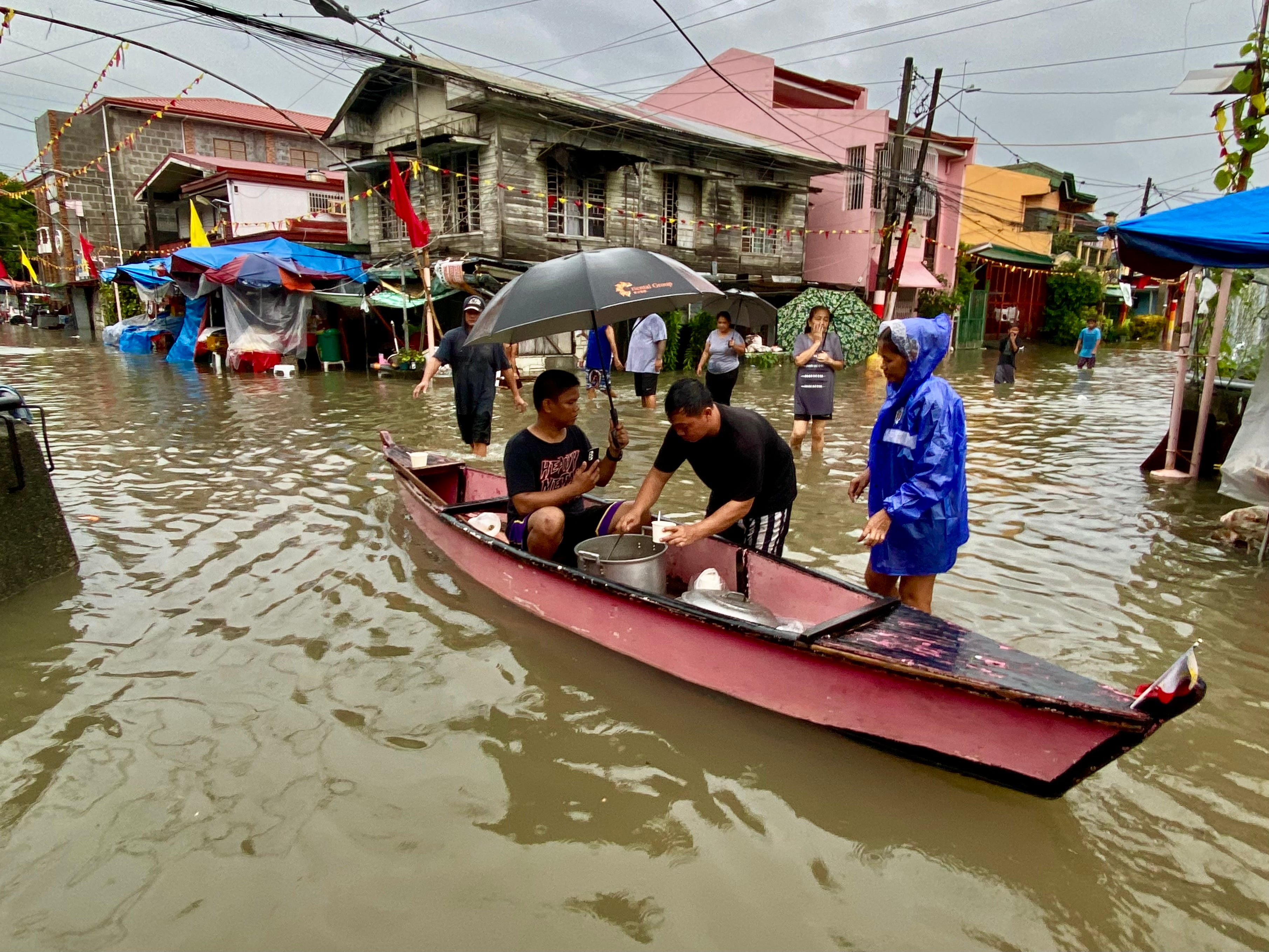 La gente camina por las aguas inundadas en la localidad de Kawit, provincia de Cavite, al sur de Manila (Filipinas), el 24 de julio de 2025.