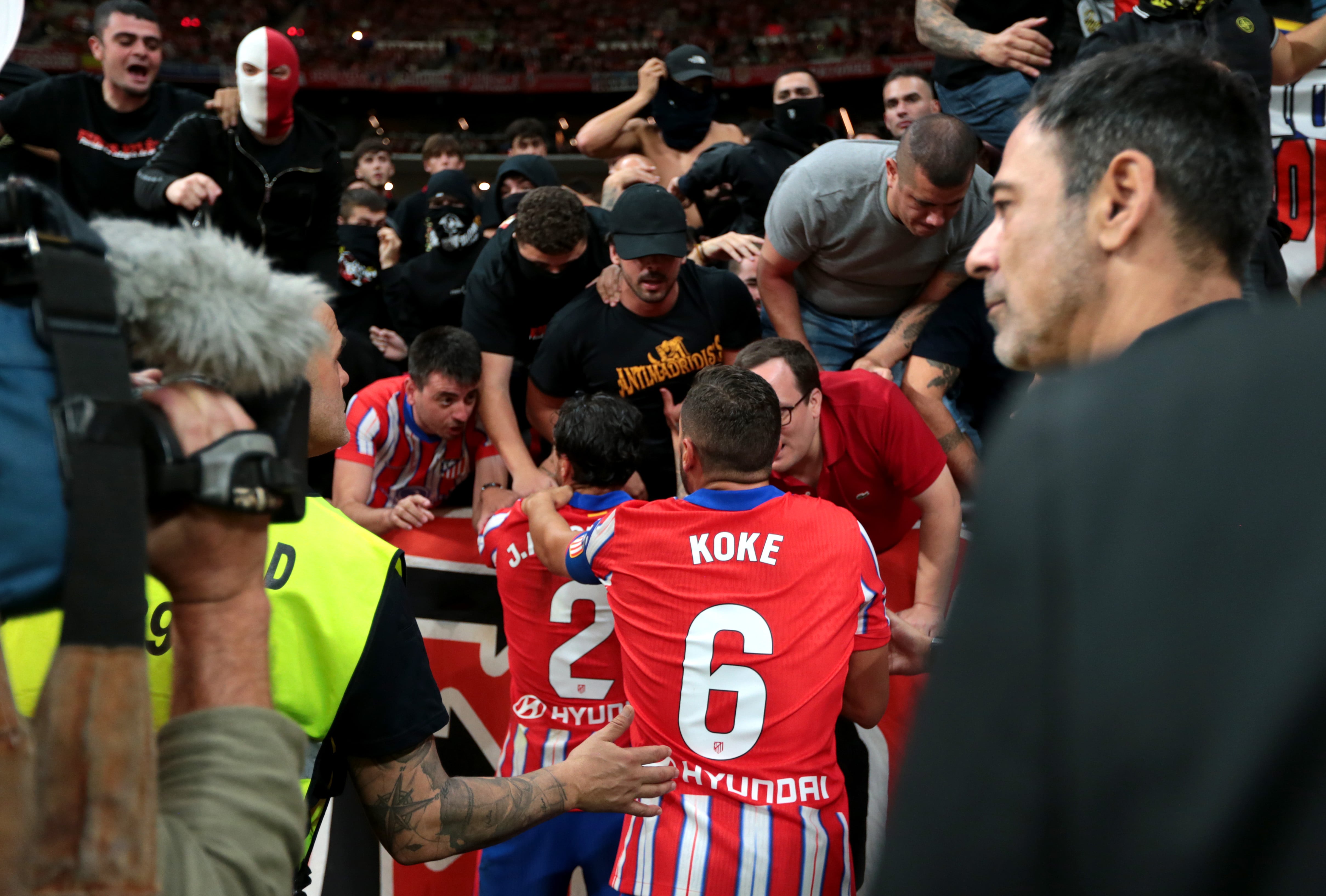 Jugadores del Atlético con aficionados radicales en el derbi madrileño