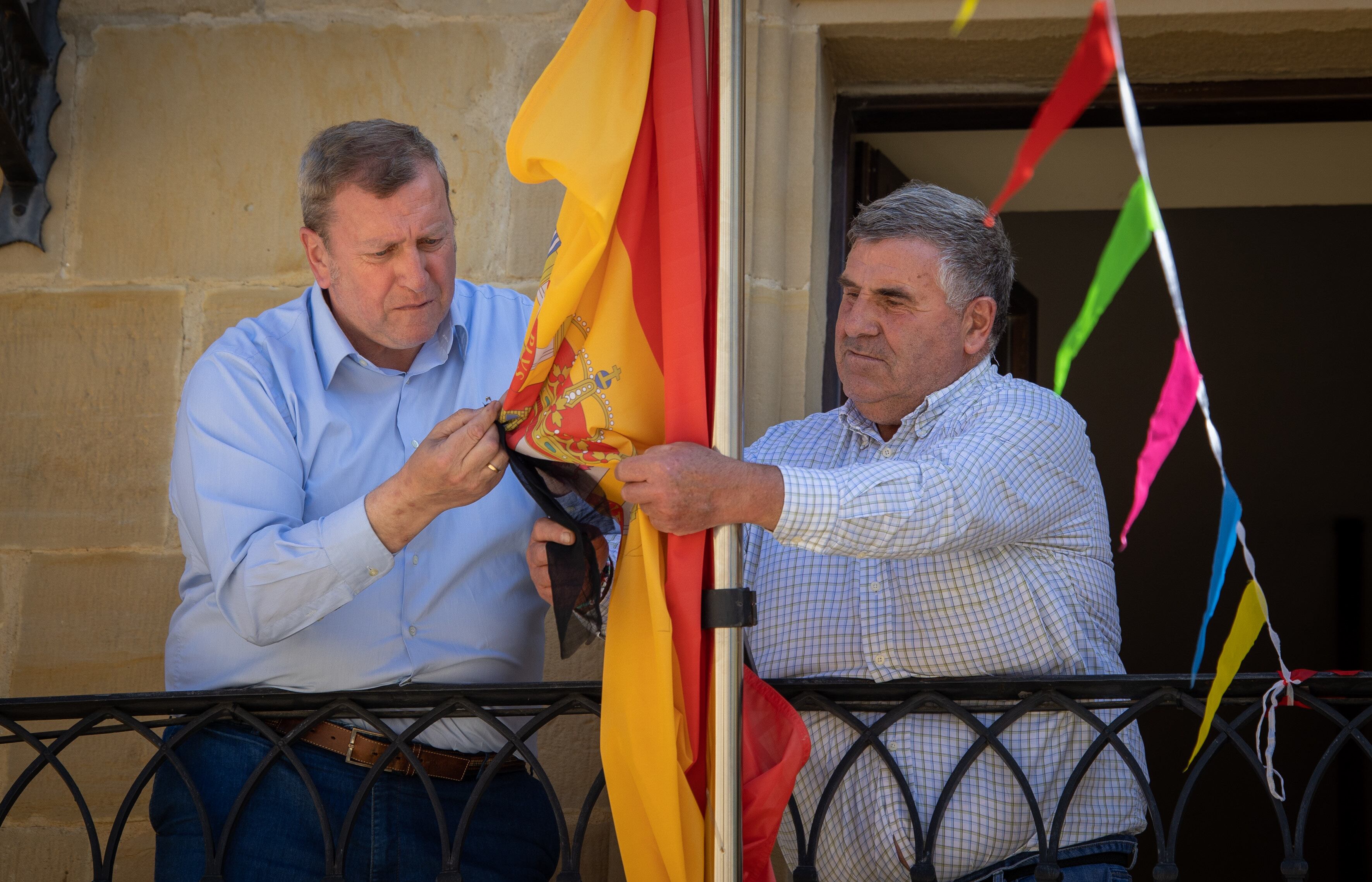 CUZCURRITA DE RÍO TIRÓN (La Rioja) 02/05/2023.- Él alcalde de la localidad, Román Urrecho (d) y el concejal Jose Luis Gobantes (i), colocan el crespón negro en la bandera del ayuntamiento, en honor al vecino fallecido. La Guardia Civil investiga la aparición del cadáver de Guillermo Castillo Herrero, hostelero, de 78 años, cuyo cuerpo ha sido encontrado este martes con signos de violencia ocasionados por arma blanca, en su domicilio de Cuzcurrita del Río Tirón (La Rioja).- EFE/Raquel Manzanares
