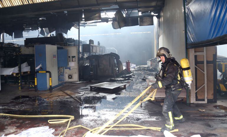 Un bombero extingue el fuego declarado en la fábrica de Macrolibros