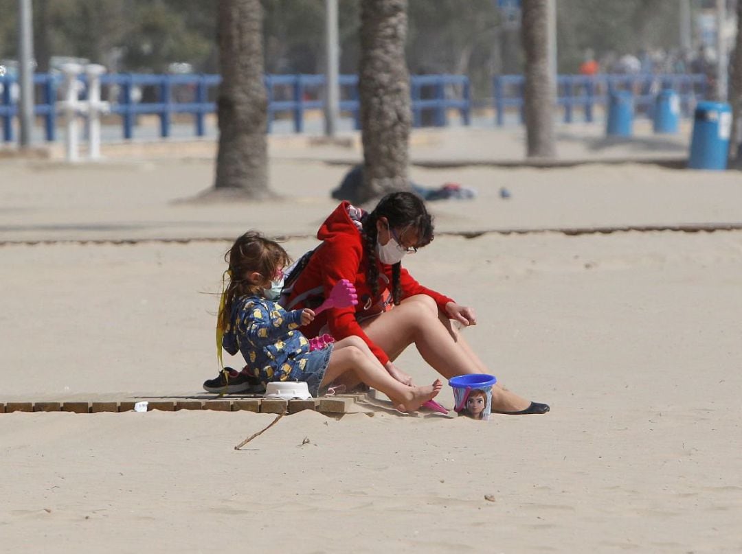 Gente en la playa con mascarilla.