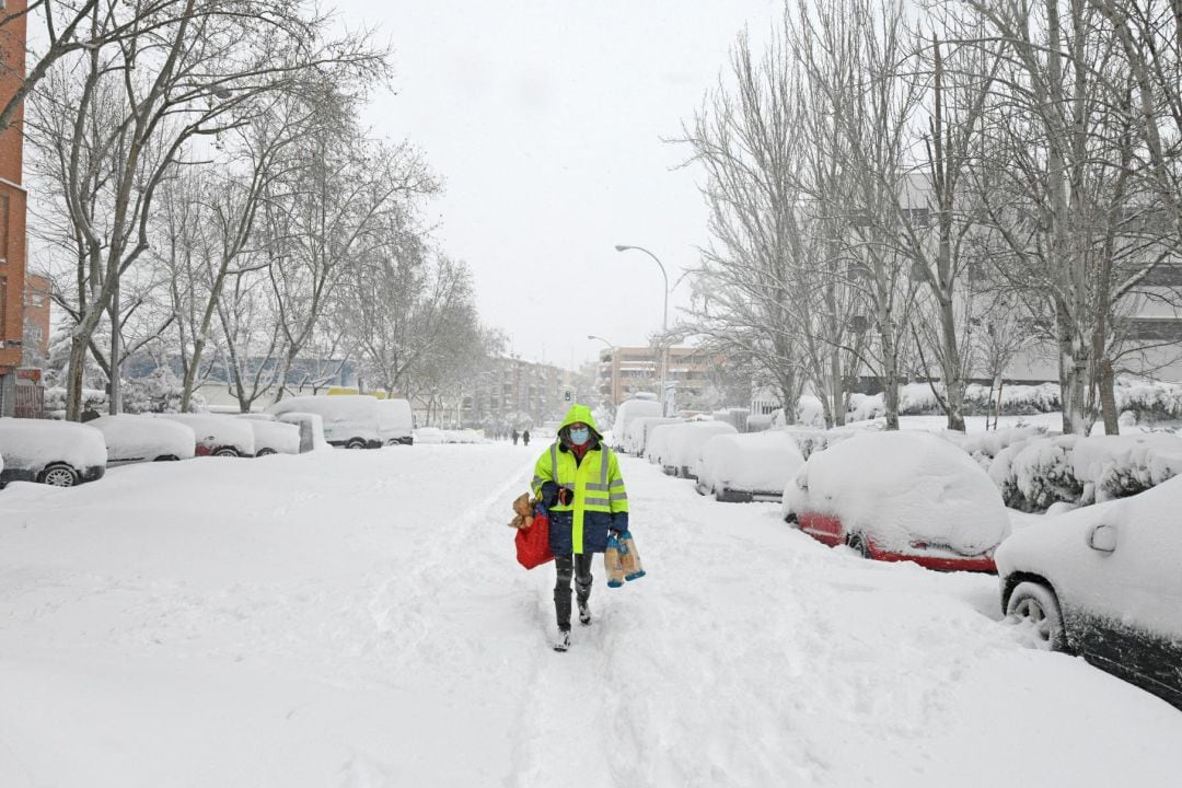 Una vecina sale a hacer la compra en Vallecas donde las calles han amanecido cubiertas de nieve en Madrid, este sábado. 