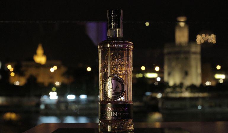 La nueva botella de la ginebra sevillana Puerto de Indias, ante su fuente de inspiración, la Torre del Oro