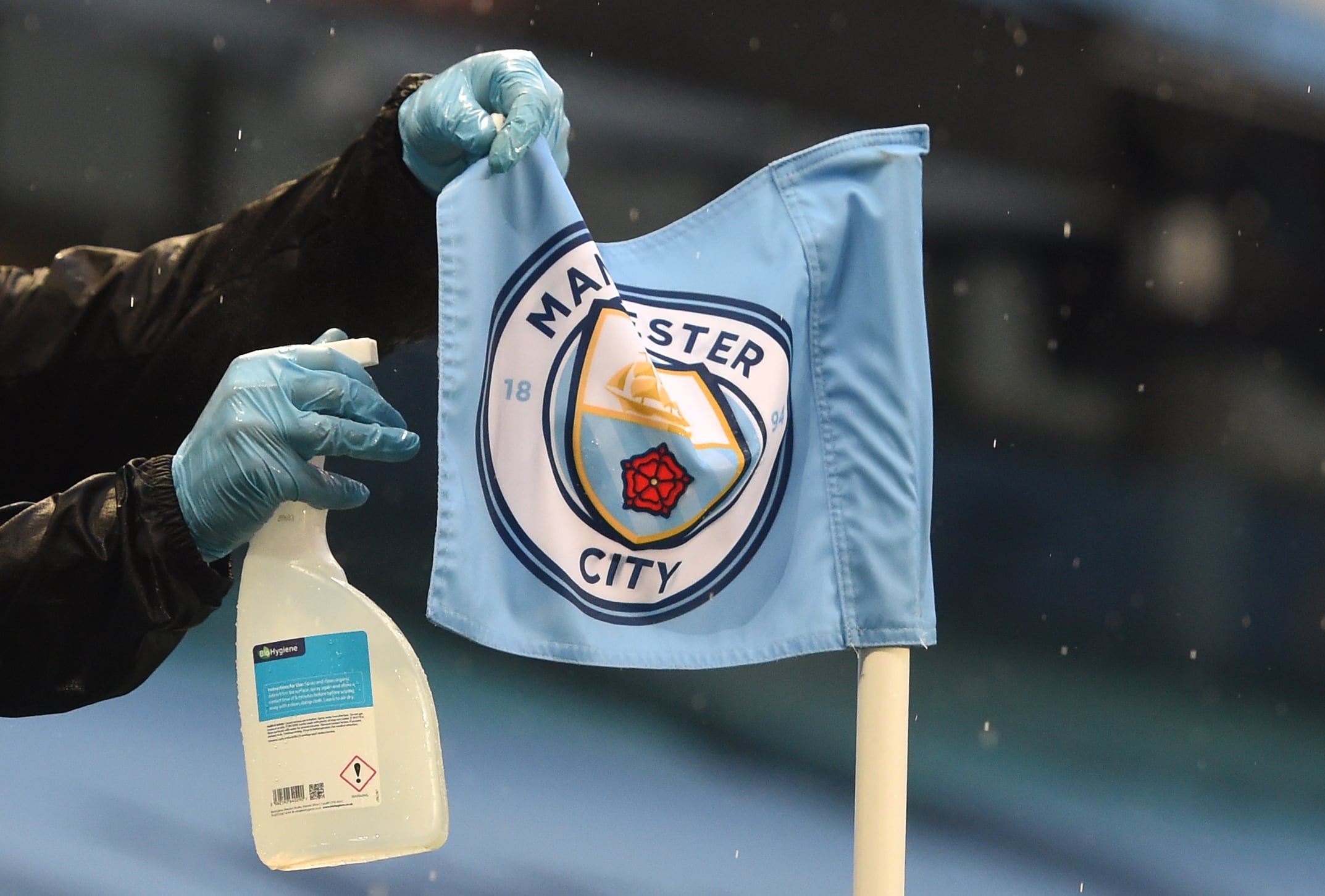 Un miembro del personal de campo rocía una bandera de esquina con un desinfectante durante el partido de fútbol de la Premier League inglesa en el estadio Etihad del Manchester City