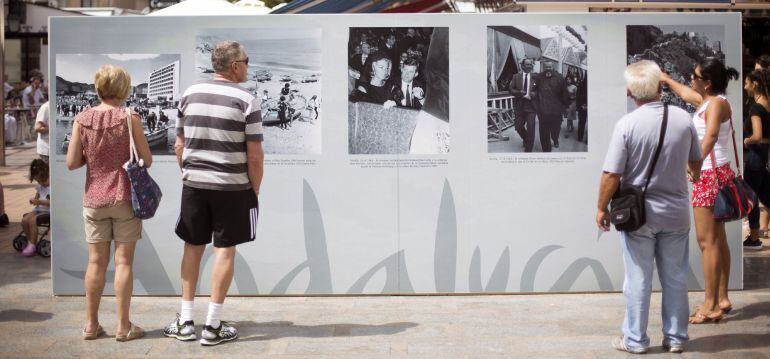 Unos turistas observan parte de la exposición &quot;Una mirada al Turismo&quot; realizada en el centro de Torremolinos con fotos del archivo de la Agencia Efe