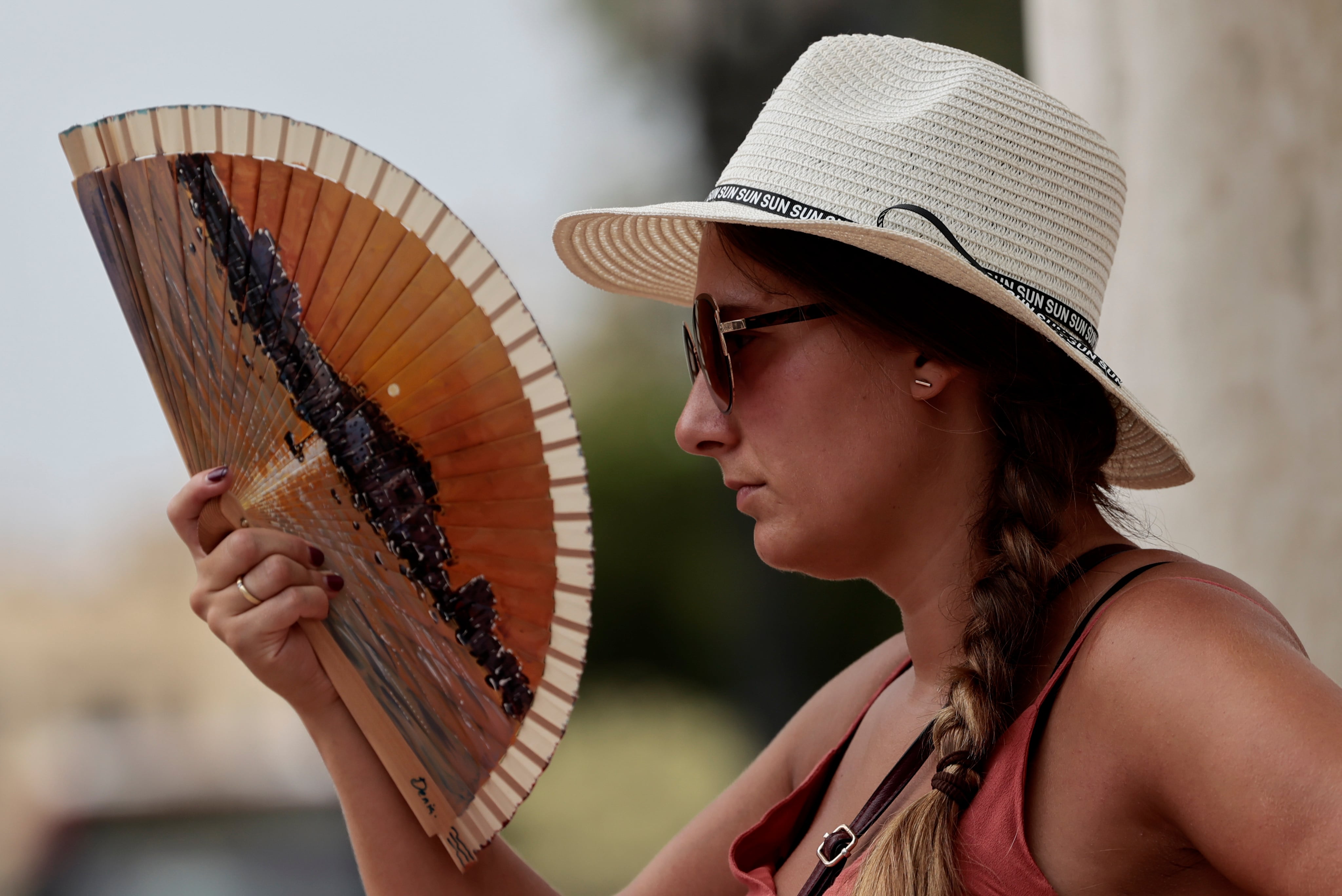 Una joven combate el calor con un abanico.