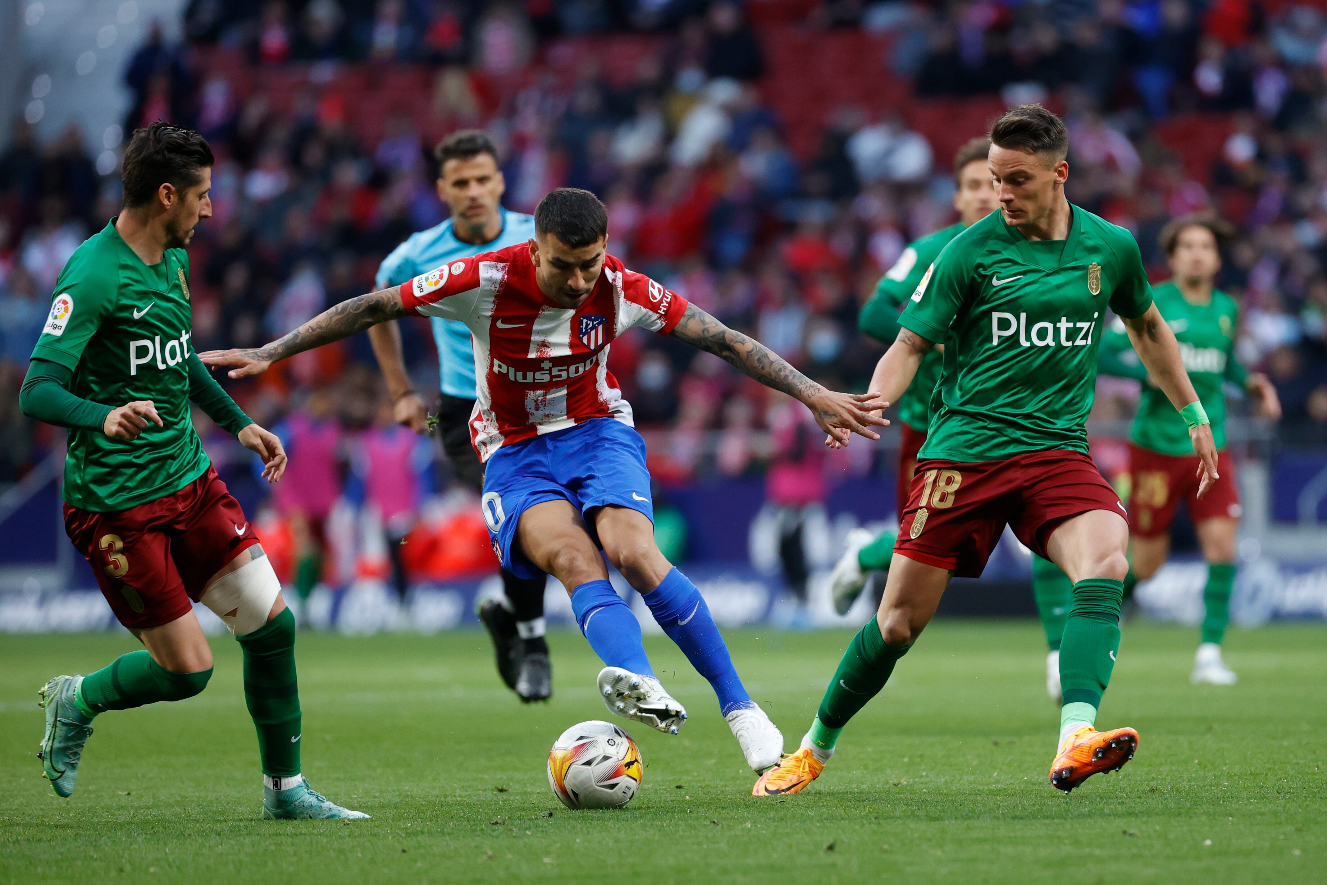 El delantero argentino del Atlético de Madrid Ángel Correa disputa el balón ante Njegos Petrovic y Sergio Escudero del Granada