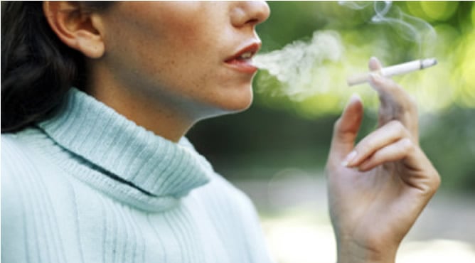 Mujer fumando en un parque infantil.