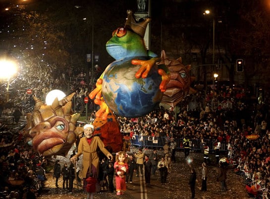 Cientos de personas observan el paso de dos marionetas gigantes que representan a un abuelo y su nieta durante la cabalgata de Reyes de Madrid, que este año rinde homenaje a los mayores