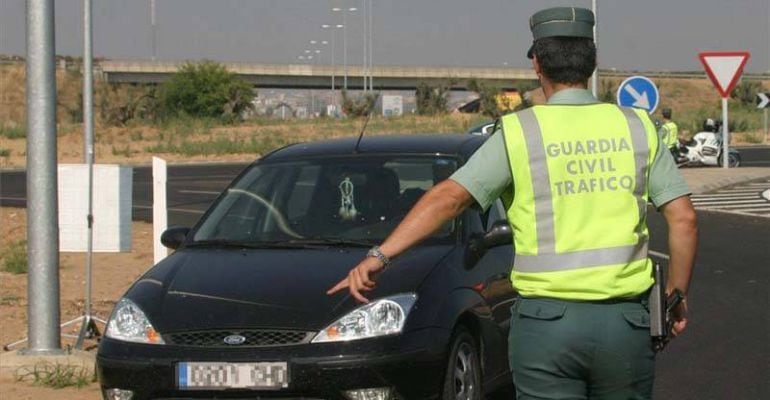 Un agente de la Guardia Civil ordena parar a un vehículo en una carretera.