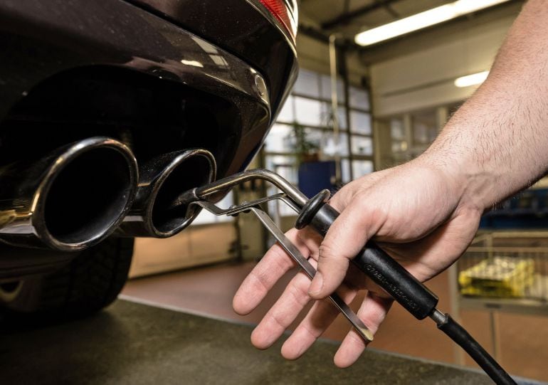 Un técnico que inspecciona el tubo de escape de un vehículo