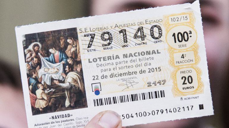 Una mujer muestra un décimo del número 79.140, en el que ha recaído el Gordo del sorteo extraordinario de la Loteria de Navidad repartido por los estudiantes del instituto Emilio Manzano de Laujar de Andarax (Almería)