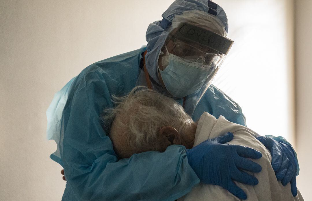 Un profesional sanitario abraza a un paciente.