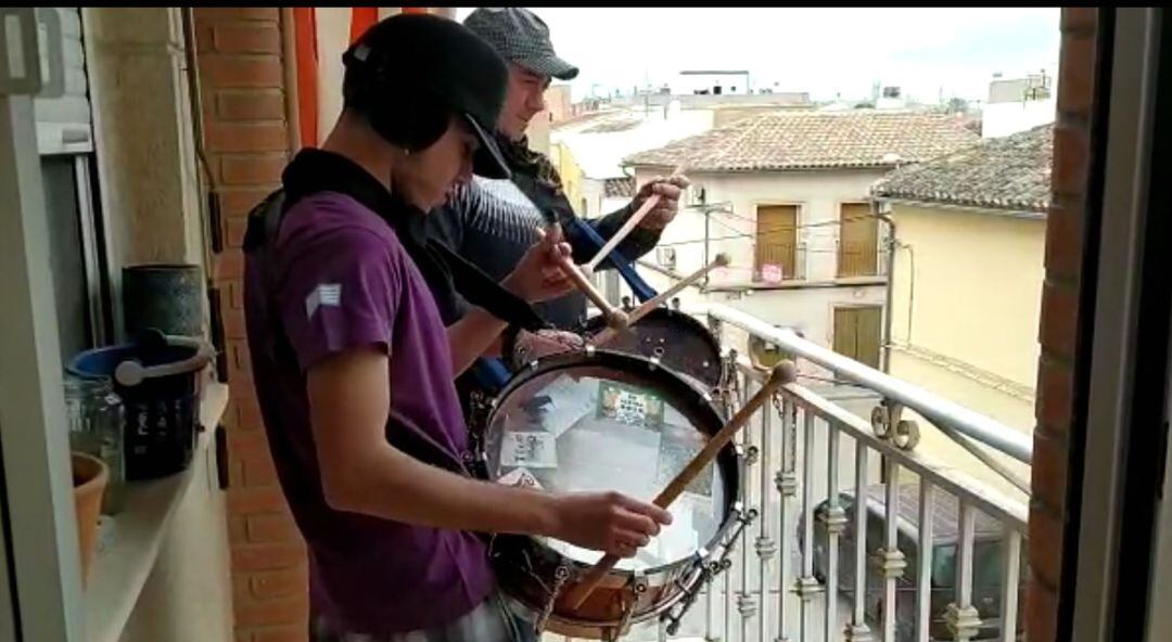 Dos tamboristas en su balcón haciendo sonar el tambor