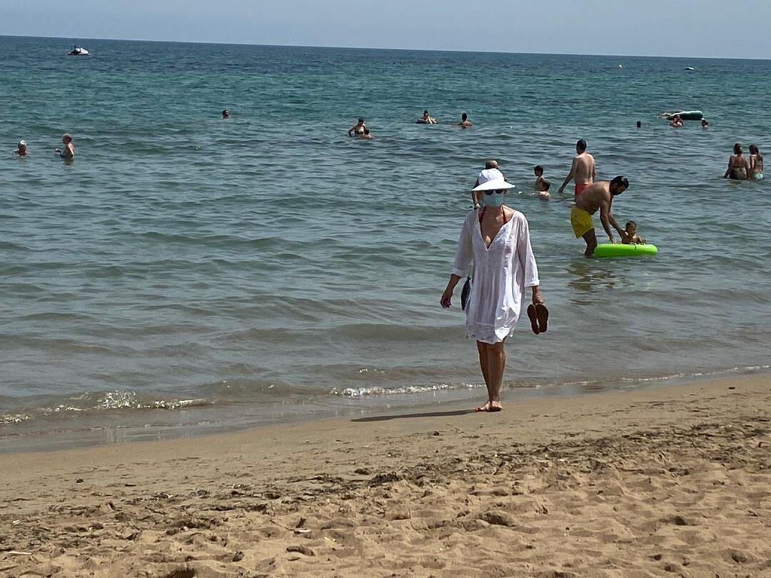 Una mujer lleva mascarilla mientras pasea en una playa de Dénia tras la recomendación del Ayuntamiento de la ciudad para utilizarlas.