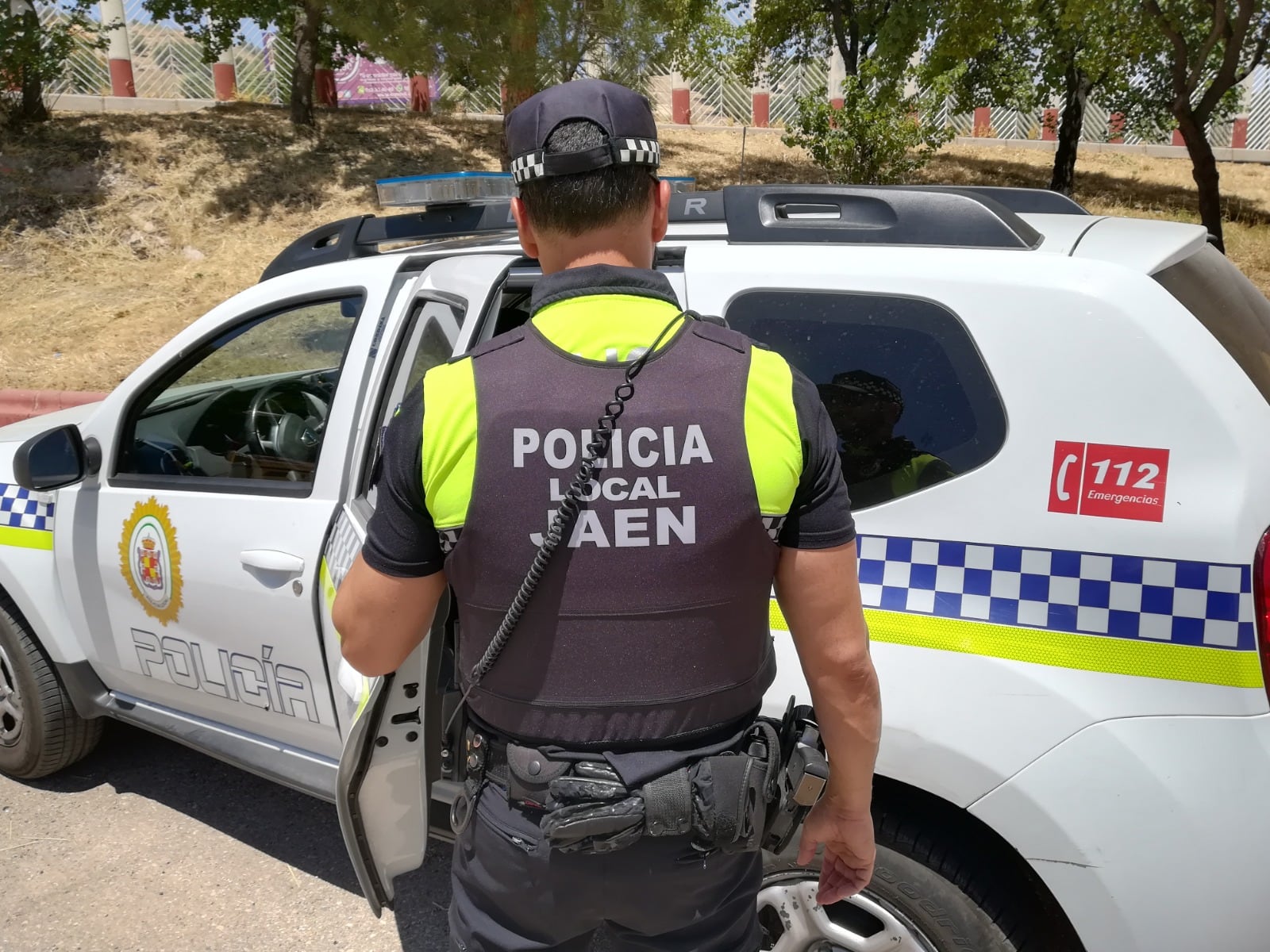 Un policía local de Jaén, de espaldas, abriendo las puertas traseras del vehículo policial