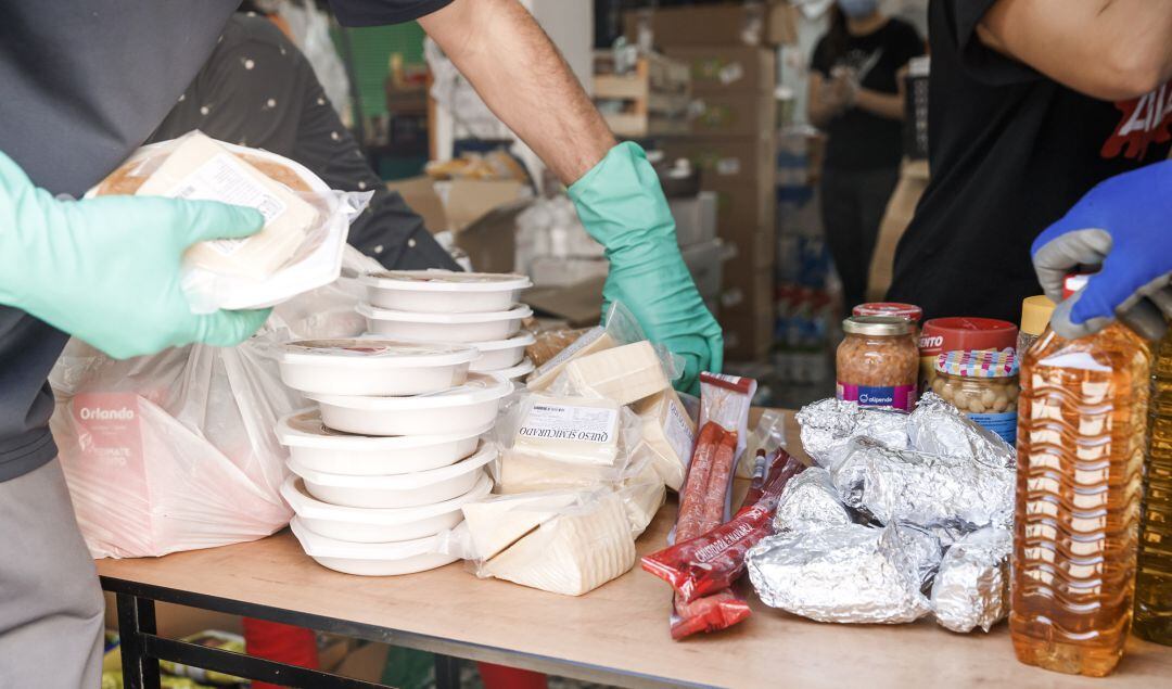 Varios voluntarios preparan paquetes de comida en un comedor social.