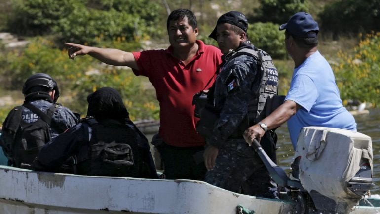 Miguel Angel Jimenez (in red), leader of the community police of Guerrero State (UPOEG), speaks with a federal police on a boat as they seek for the 43 Ayotzinapa students&#039; missing, in Acatlan, in the southwestern state of Guerrero, October 30, 2014. Jime