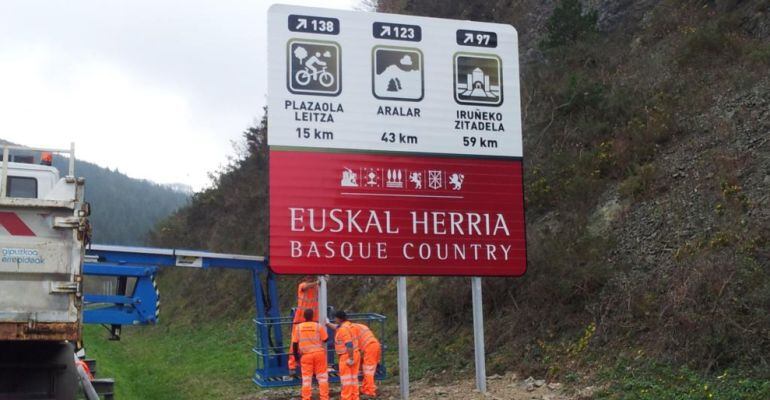 Uno de los polémicos carteles, siendo colocado en una de las carreteras guipuzcoanas, con varias referencias a Navarra.