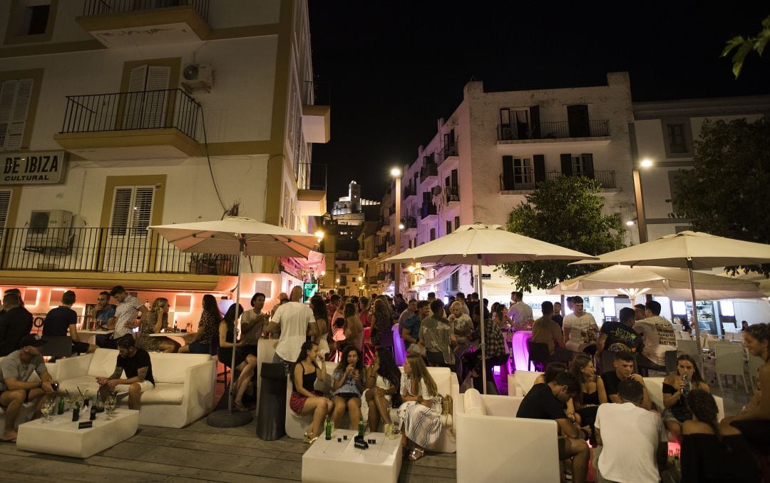 Decenas de personas toman algo en la terraza de un bar.